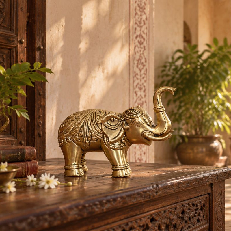 A decorative brass elephant figurine stands on a carved wooden table in a sunlit traditional courtyard with hanging benches, potted plants, and warm architectural details.
